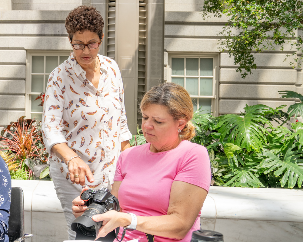Teacher showing student how to work camera settings in photo class for beginners.
